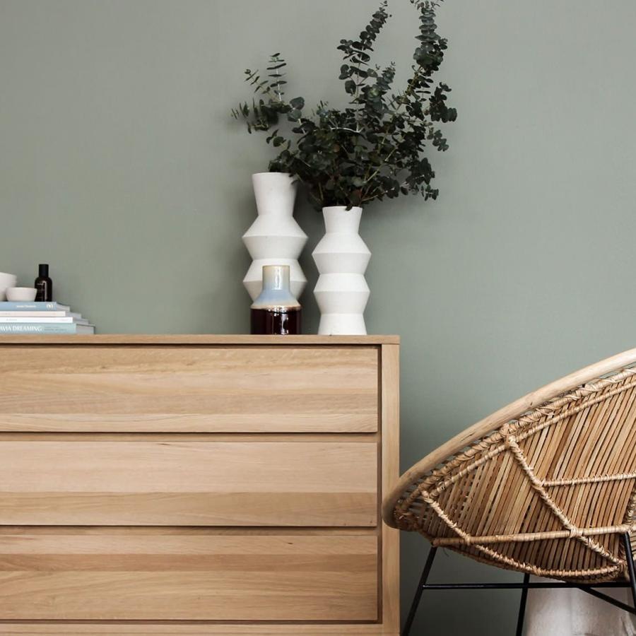 decor on a tall, wooden dresser next to a papasan chair with a throw