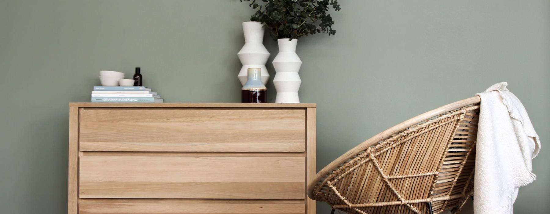 decor on a tall, wooden dresser next to a papasan chair with a throw